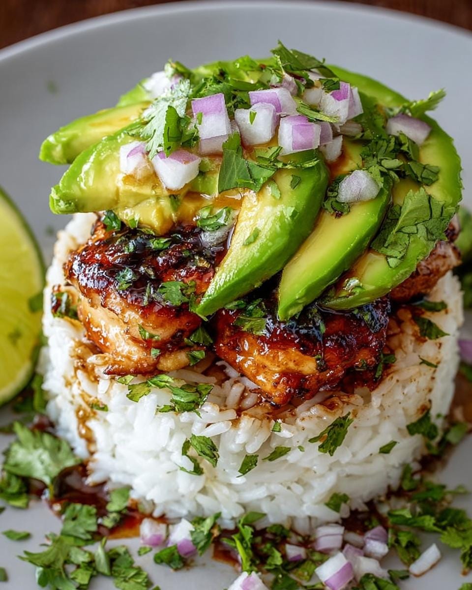A delicious Honey Lime Chicken Avocado Rice Stack topped with fresh avocado slices, red onion, and cilantro.