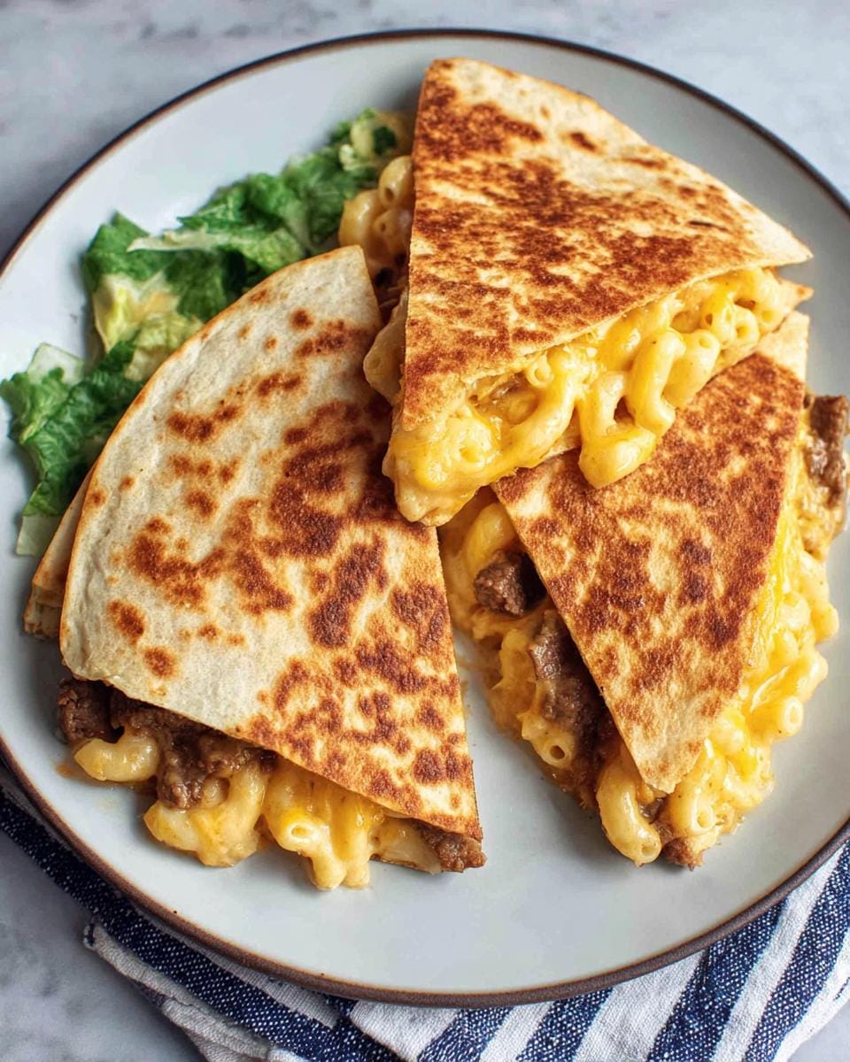 A plate of easy mac and cheese quesadilla, cut into wedges, filled with gooey cheese and pasta, served with lettuce.
